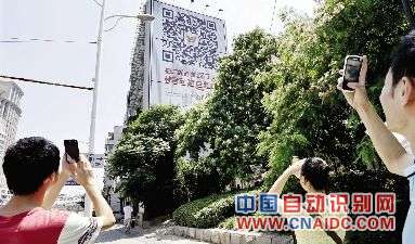昨日,解放大道香港路口,市民用手机扫描墙体广告上的二维码。本报记者 傅坚 摄